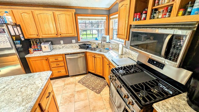 kitchen with stainless steel appliances, a sink, light tile patterned floors, and crown molding