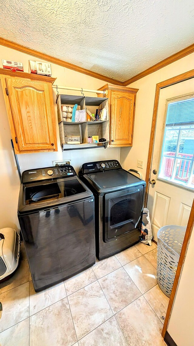 clothes washing area with light tile patterned floors, crown molding, separate washer and dryer, cabinet space, and a textured ceiling