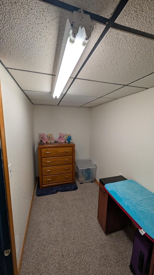 carpeted bedroom featuring a paneled ceiling and baseboards