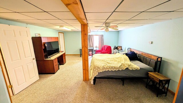 bedroom with a drop ceiling, baseboards, and light carpet