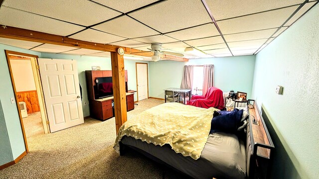 carpeted bedroom featuring a paneled ceiling and baseboards