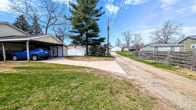 view of yard with driveway, a carport, and fence