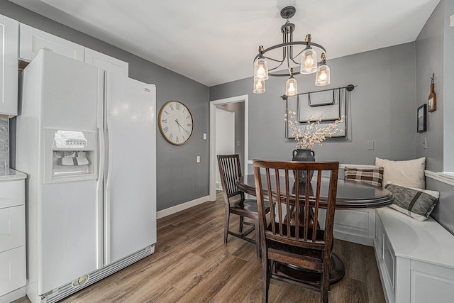 dining space featuring baseboards, wood finished floors, and a notable chandelier