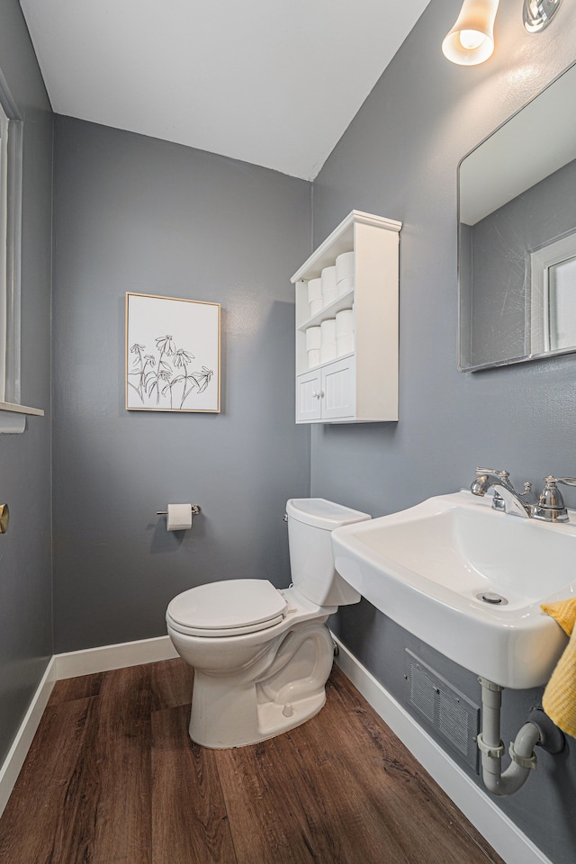half bath featuring toilet, baseboards, and wood finished floors