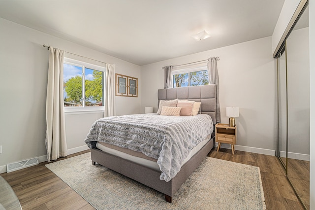 bedroom with visible vents, baseboards, wood finished floors, and a closet