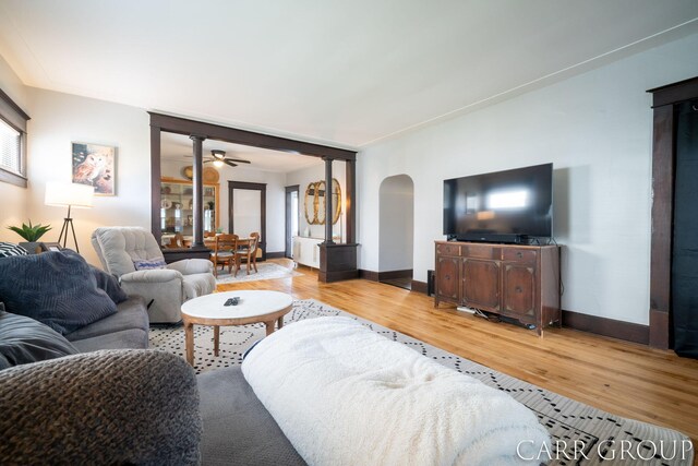 living room with baseboards, a ceiling fan, wood finished floors, and arched walkways