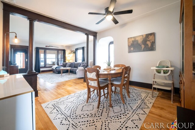 dining area featuring ceiling fan, arched walkways, light wood-style flooring, and ornate columns