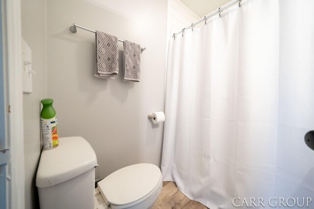 full bath with curtained shower, wood finished floors, and toilet