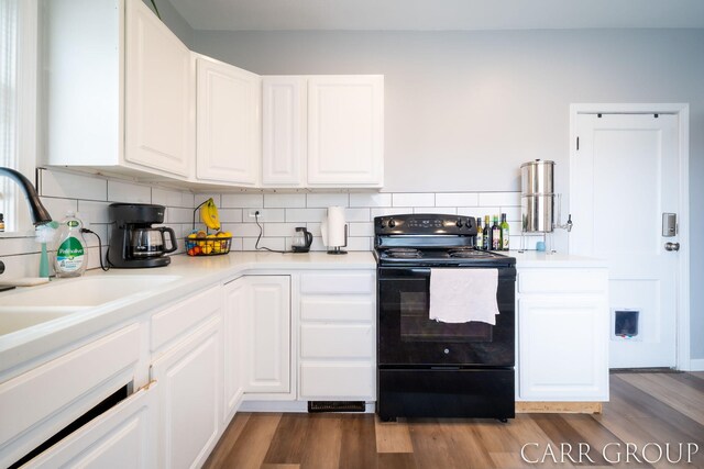 kitchen with white cabinets, tasteful backsplash, wood finished floors, and black electric range