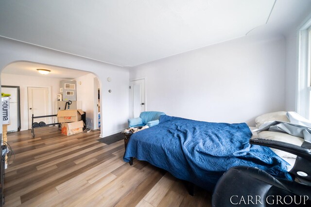 bedroom with wood finished floors and arched walkways