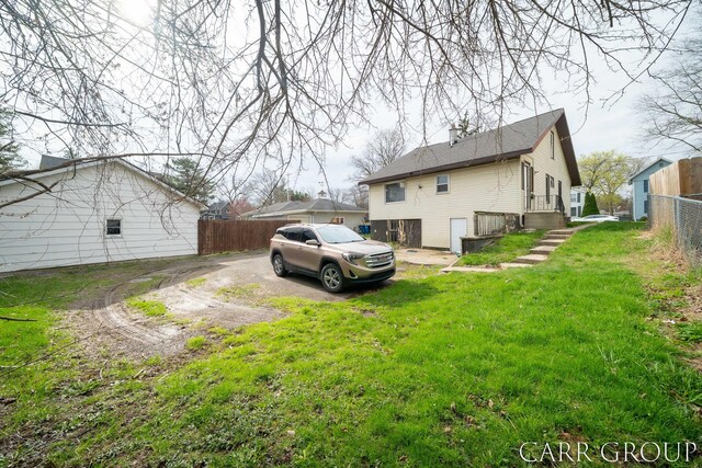 view of side of home featuring a chimney, fence, and a yard