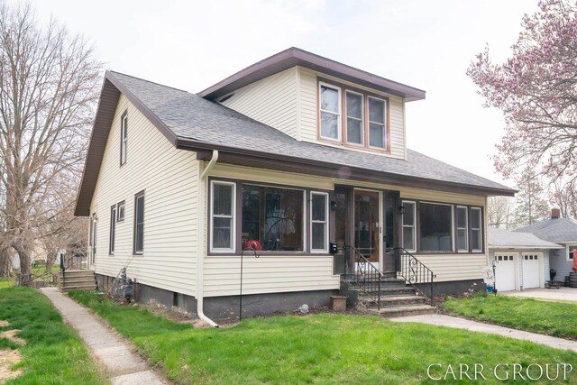 bungalow-style home featuring an attached garage, a front lawn, and roof with shingles