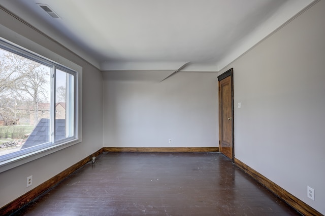 spare room featuring baseboards, wood finished floors, and visible vents