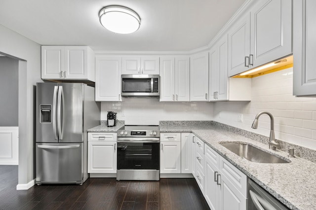 kitchen with a sink, appliances with stainless steel finishes, dark wood-style flooring, and white cabinetry