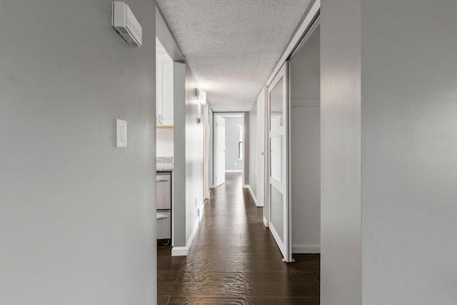 hallway featuring baseboards, a textured ceiling, and dark wood-style flooring