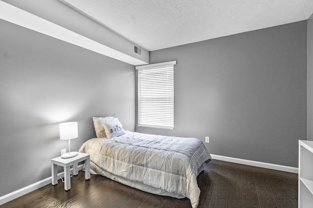 bedroom with baseboards, a textured ceiling, and visible vents