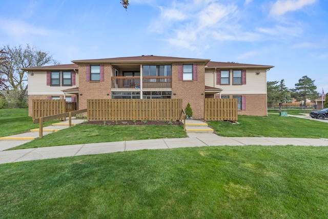 view of front of house with brick siding, fence, a balcony, and a front yard