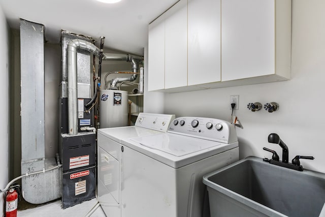 washroom with cabinet space, washing machine and dryer, a sink, and water heater