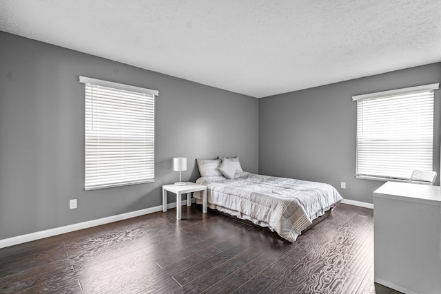 bedroom with baseboards, a textured ceiling, and wood finished floors
