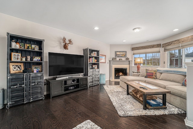 living room with recessed lighting, a warm lit fireplace, and hardwood / wood-style flooring