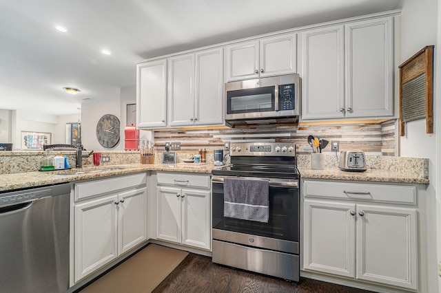kitchen featuring dark wood-style flooring, white cabinetry, a sink, appliances with stainless steel finishes, and backsplash