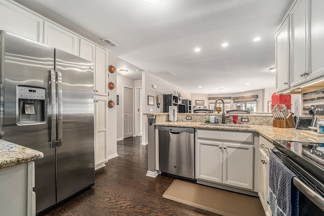 kitchen with visible vents, dark wood finished floors, a sink, a peninsula, and stainless steel appliances