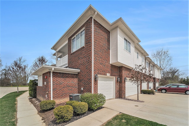 view of property exterior with brick siding, an attached garage, central air condition unit, and driveway