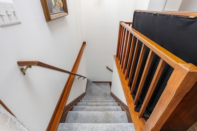 stairway with wood finished floors and baseboards