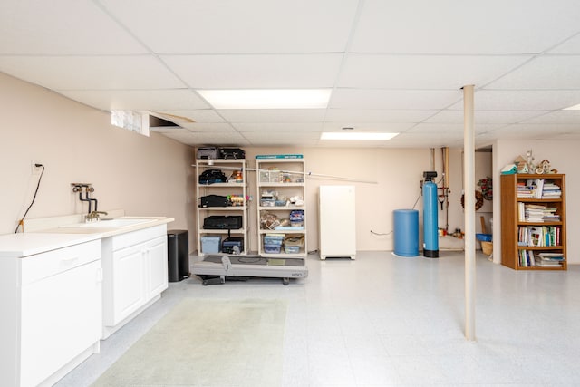 finished basement featuring a paneled ceiling and a sink