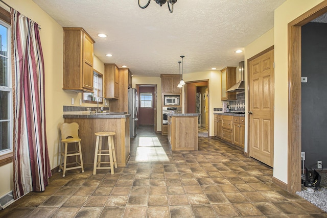 17026 H Dr S, Marshall, MI 49068 - kitchen with dark countertops, wall chimney exhaust hood, appliances with stainless steel finishes, and a kitchen island