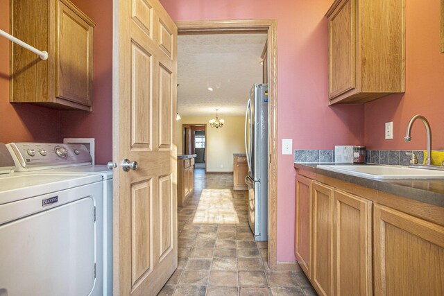 17026 H Dr S, Marshall, MI 49068 - laundry room with washer and clothes dryer, stone finish floor, a sink, cabinet space, and a notable chandelier