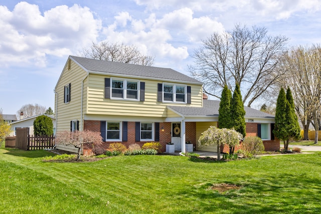view of front of house with brick siding, fence, and a front lawn