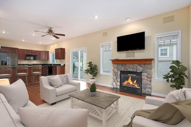 living area with recessed lighting, a stone fireplace, visible vents, a ceiling fan, and light wood-type flooring
