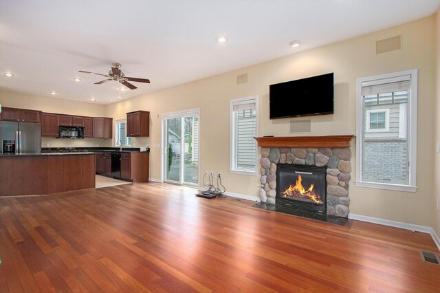 unfurnished living room featuring a fireplace, wood finished floors, visible vents, and baseboards