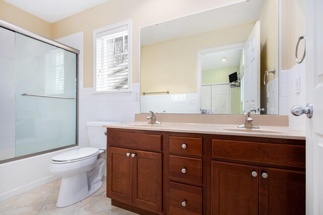 full bathroom featuring tile walls, tile patterned flooring, toilet, and a sink