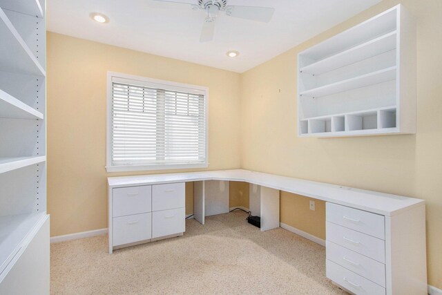 unfurnished office featuring light carpet, baseboards, and ceiling fan