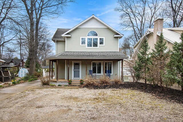view of front of home featuring a porch, a storage unit, an outdoor structure, and roof with shingles