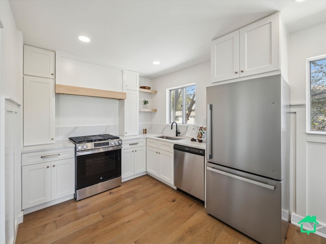 kitchen featuring appliances with stainless steel finishes, white cabinetry, open shelves, and a sink
