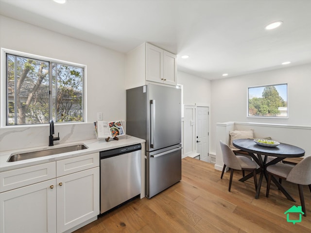 kitchen featuring light wood-style flooring, white cabinets, a sink, appliances with stainless steel finishes, and recessed lighting