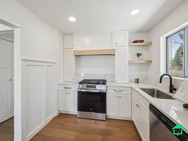 kitchen featuring a sink, open shelves, stainless steel appliances, and white cabinetry
