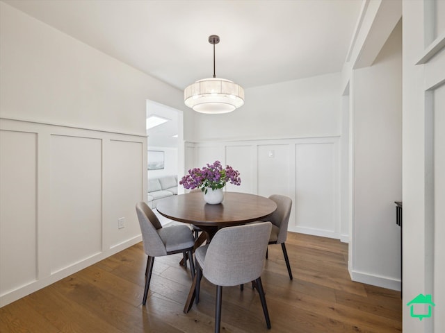 dining room with a wainscoted wall, wood finished floors, and a decorative wall