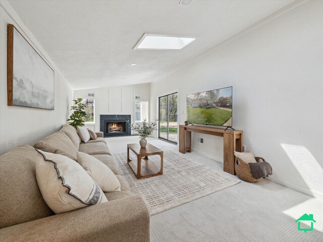 living area with carpet, a premium fireplace, crown molding, and vaulted ceiling with skylight