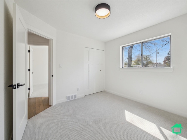 unfurnished bedroom featuring carpet flooring, a closet, visible vents, and baseboards
