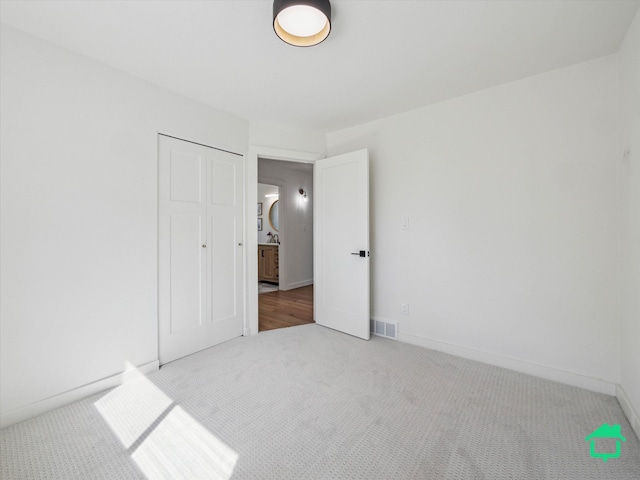 unfurnished bedroom featuring visible vents, a closet, baseboards, and carpet floors