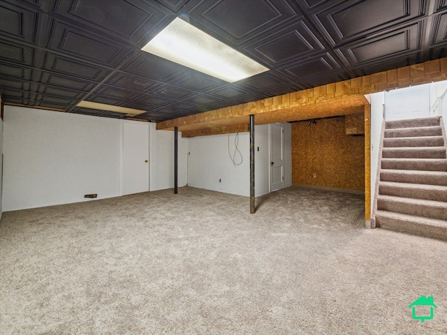 finished below grade area featuring stairway, carpet, and an ornate ceiling