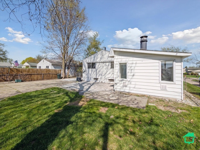 back of house featuring fence, a chimney, a yard, and a patio