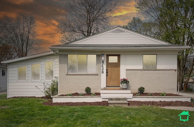 view of front of home with a yard and brick siding