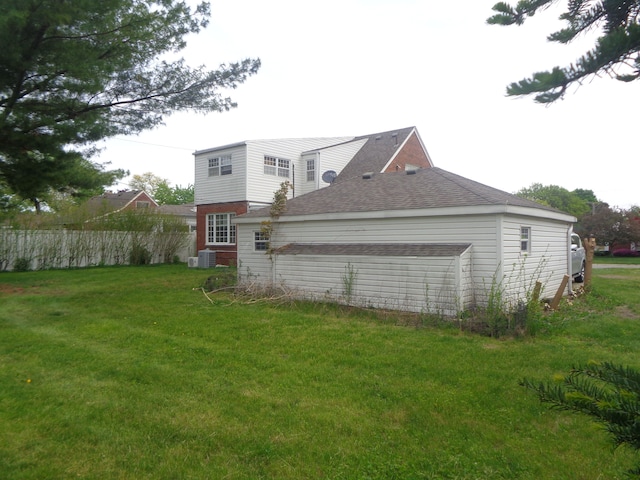 1353 N Gulley Rd, Dearborn Heights, MI 48127 - rear view of property featuring fence, a lawn, roof with shingles, and central AC unit