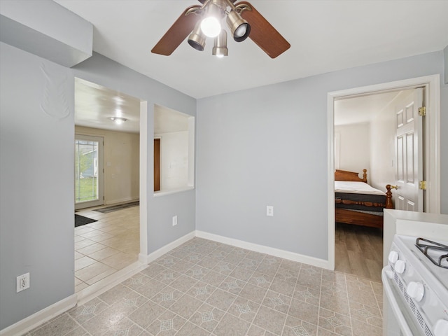 spare room with baseboards and a ceiling fan