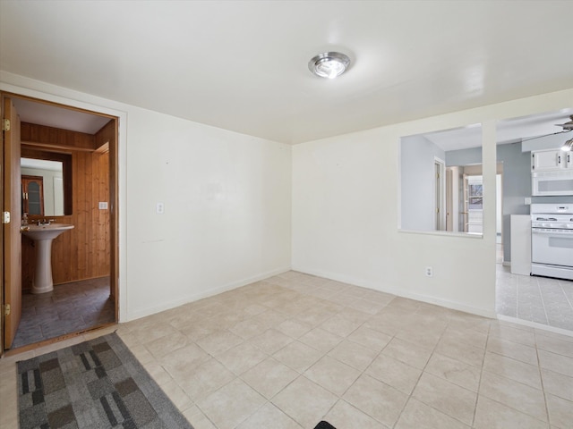empty room with light tile patterned floors, baseboards, and a sink